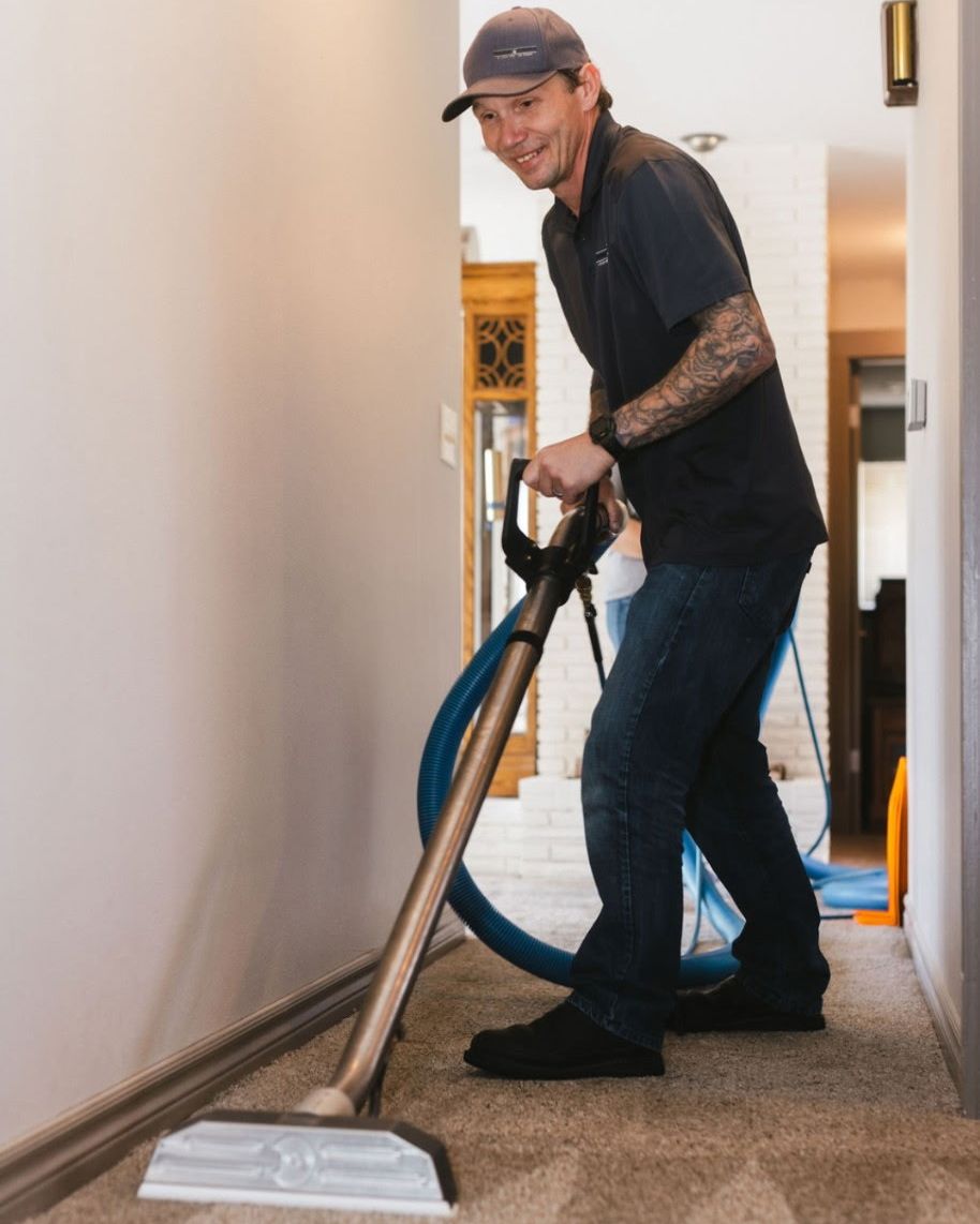 Raindrop Cleaning technician cleaning hallway carpet with a wand